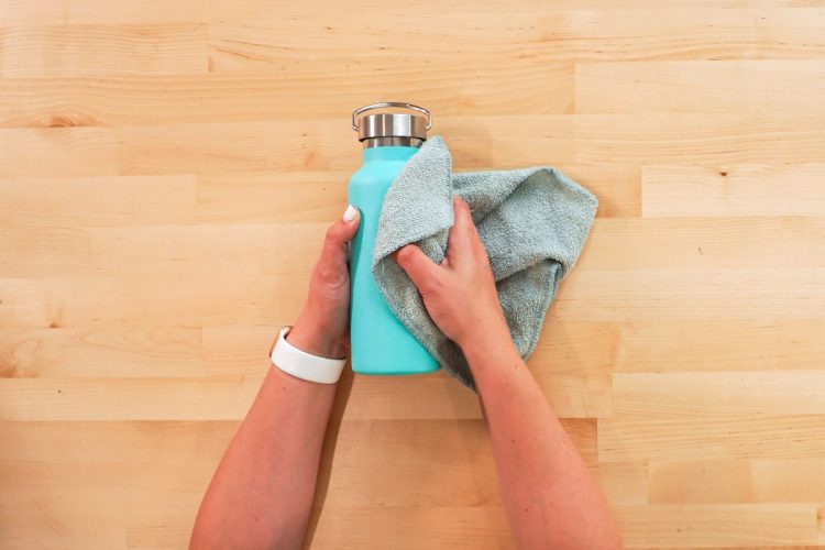 hands wiping the etched powder coating from the tumbler using a washcloth