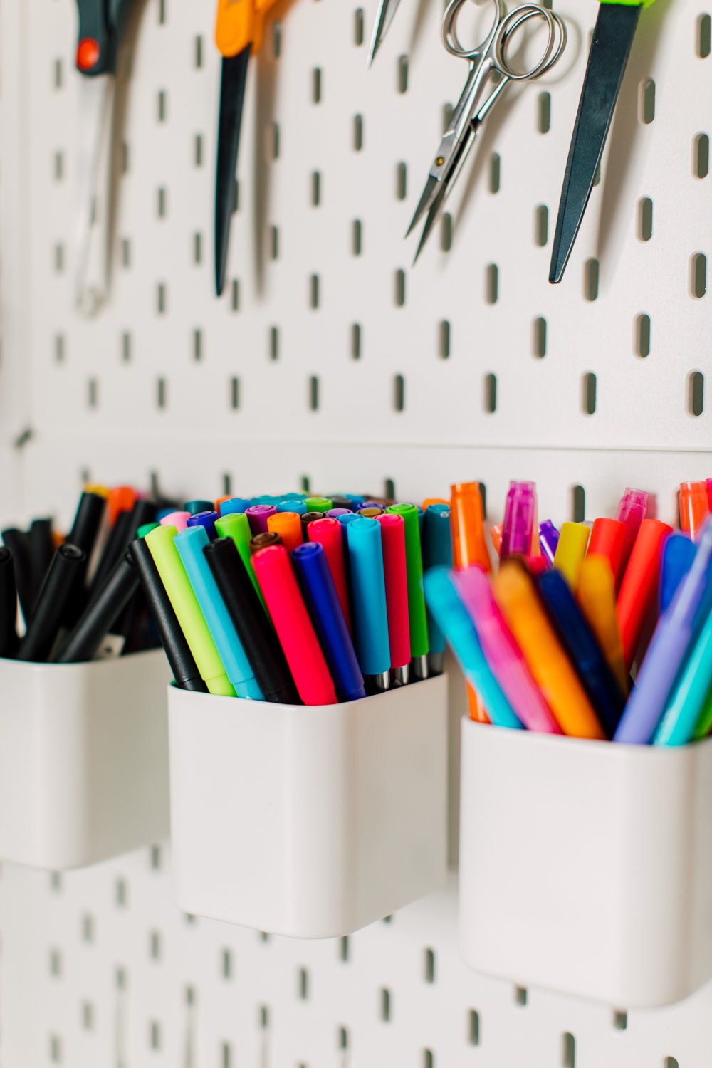 Close up of pens in containers on a pegboard