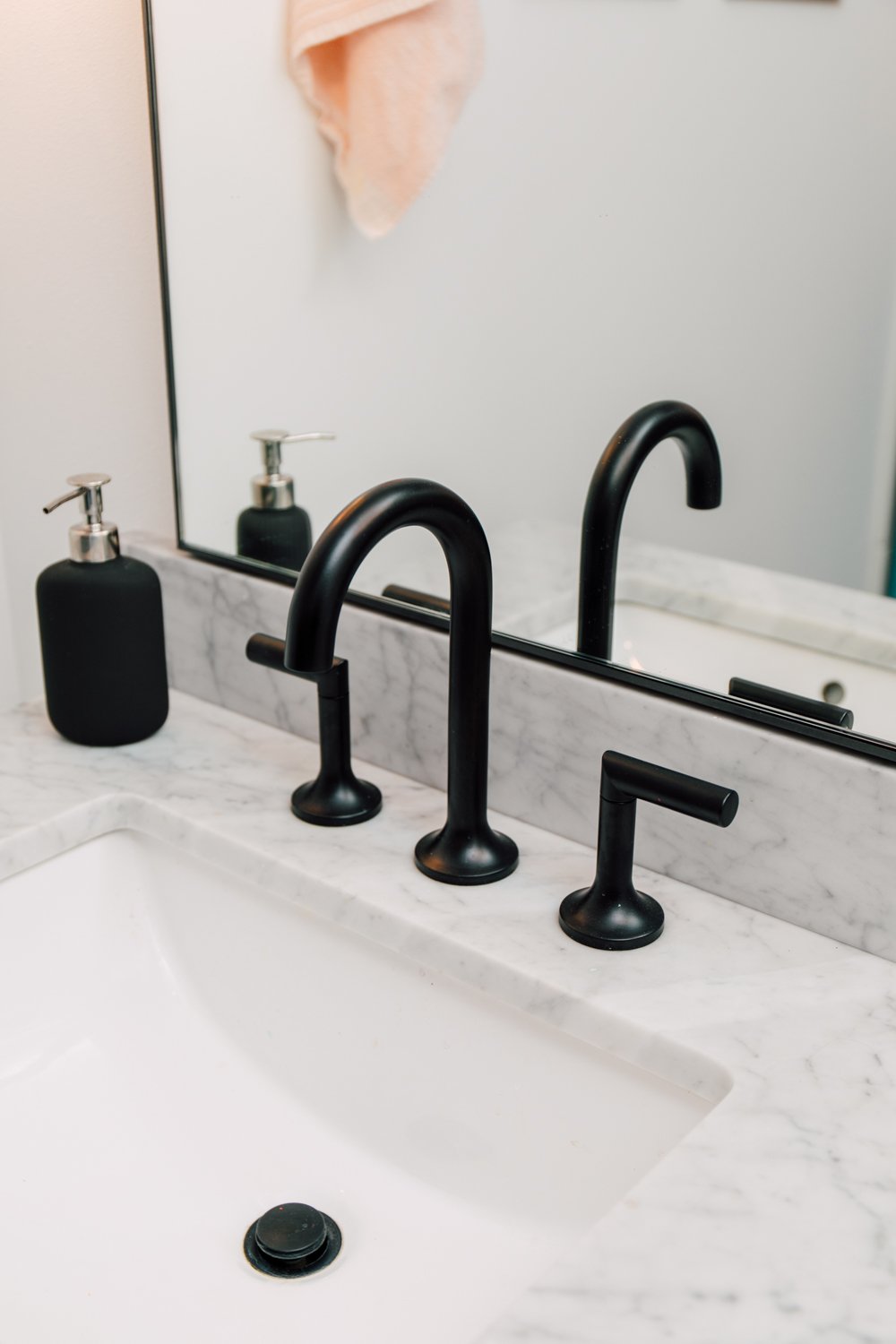 Close up of sink in bathroom with black faucet.
