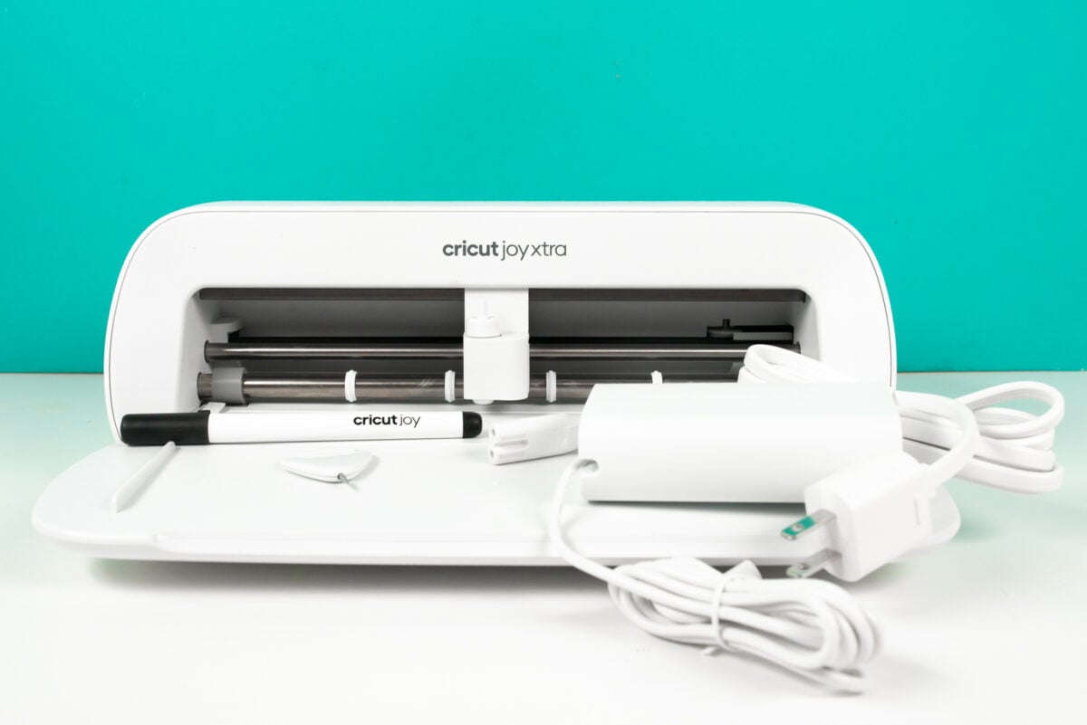 Cricut Joy Xtra machine with pen, weeding tool, and cord.