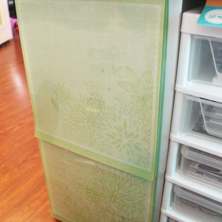 Cricut mats hanging from a command hook on the side of a Cricut table