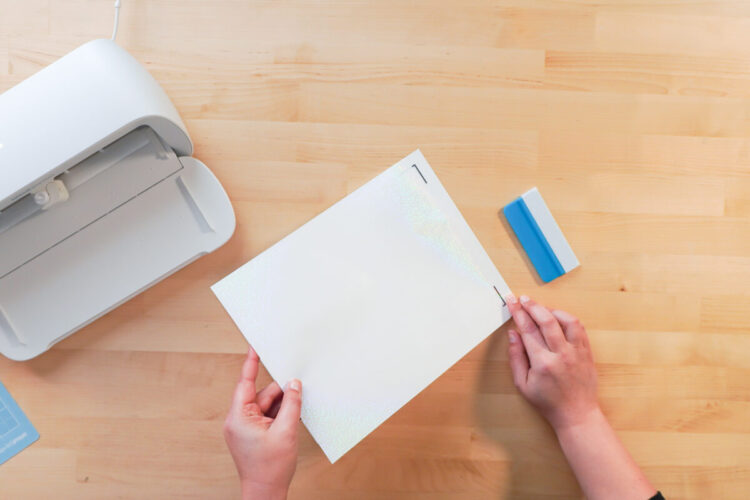 Hands applying the waterproof vinyl to the printed sheet