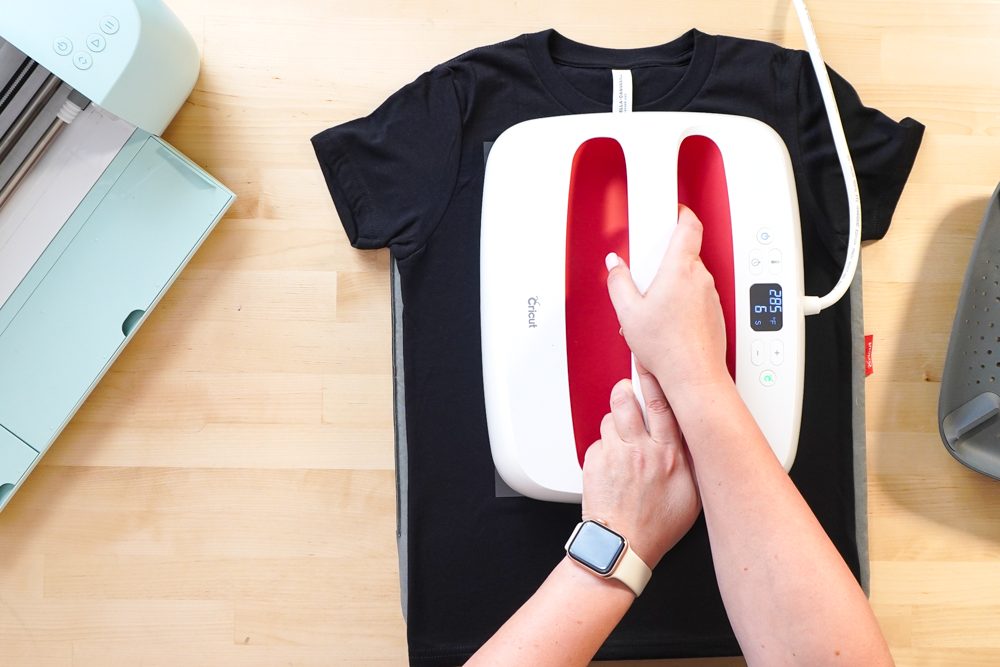 Hands pressing the black t-shirt with an EasyPress