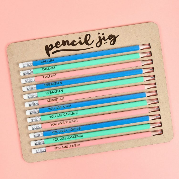 Pencil jig with finished pencils on pink background.