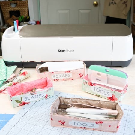 A Cricut machine and three storage bins made out of fabric