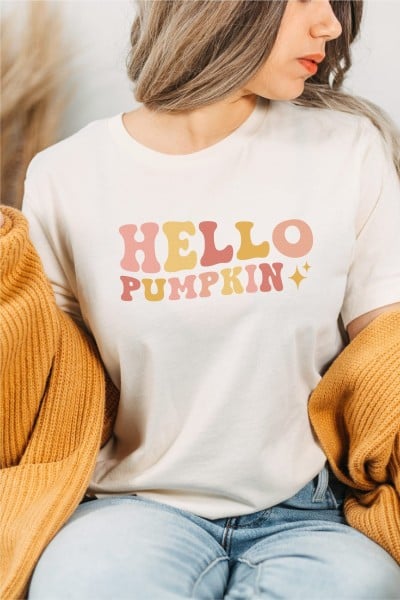 Woman wearing an orange sweater and a white t-shirt that says Hello Pumpkin