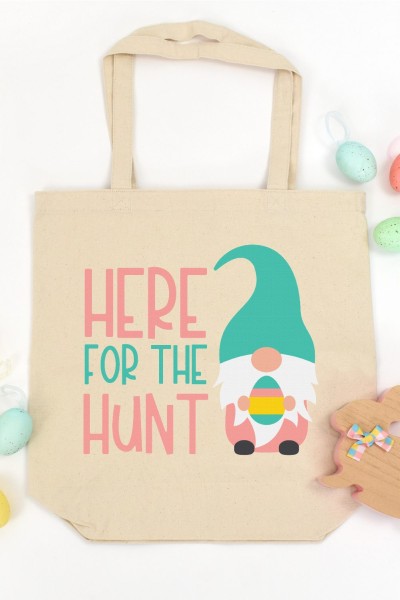 Easter eggs, wooden bunny and a tote bag with a picture of a gnome holding an Easter egg and the saying Here for the hunt