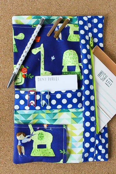 A close up of a planner organizer with a pen, paper and clips on it