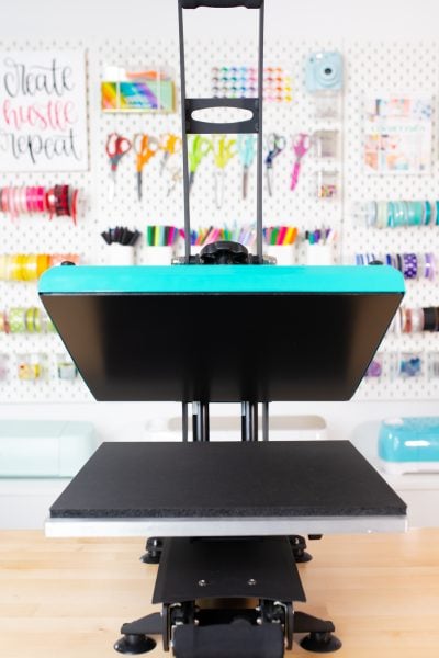 Open teal WALApress facing forward on workbench with crafty pegboard behind.