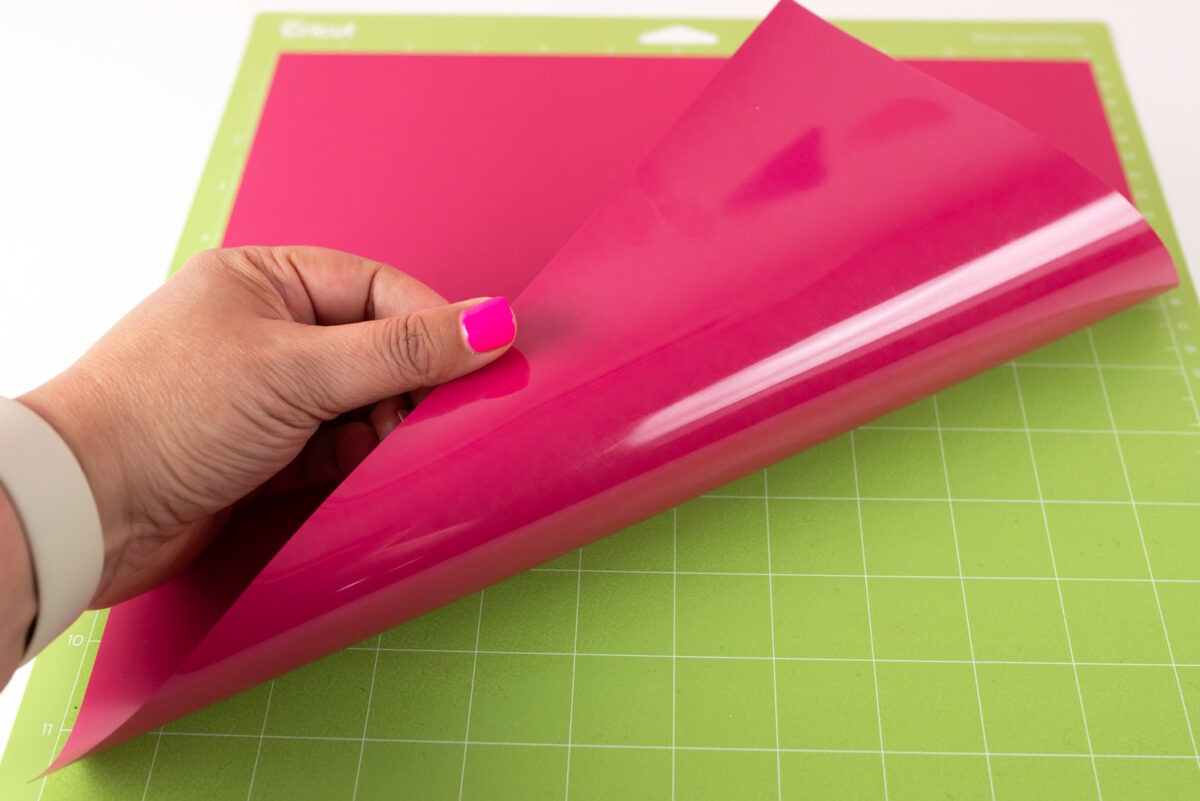 Hand showing HTV shiny side down on mat