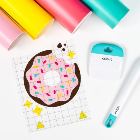 Final layered donut image with rolls of vinyl and Cricut tools.