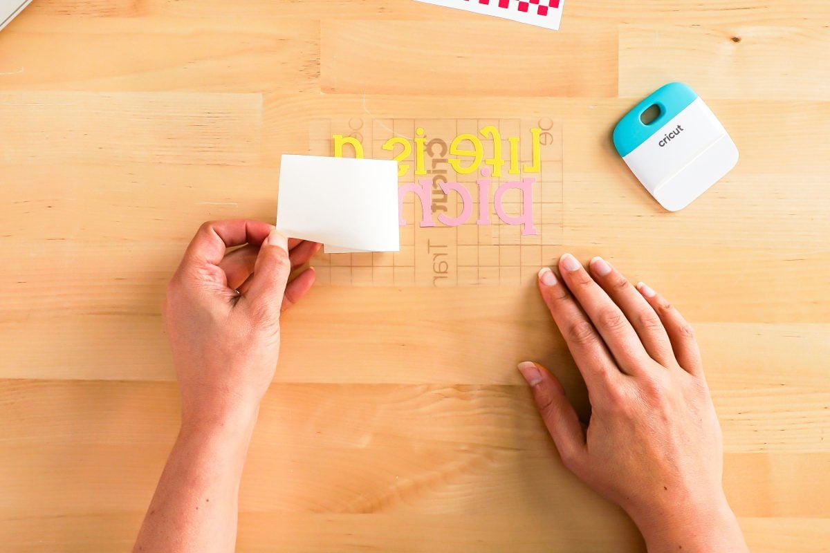 Hands peeling back transfer tape liner.