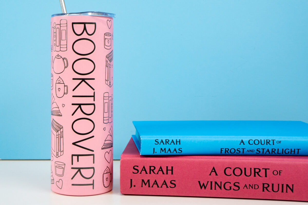 "Booktrovert" tumbler with a stack of books