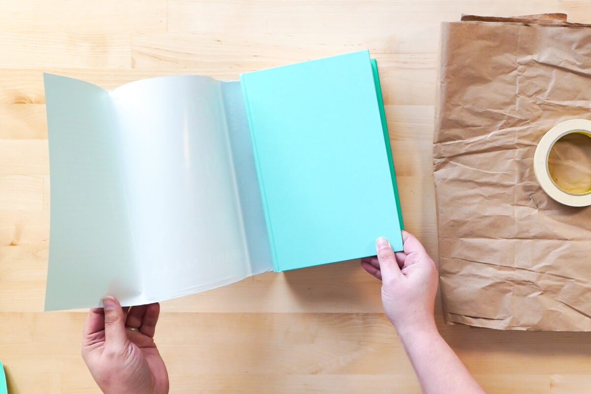 Hands removing the book cover