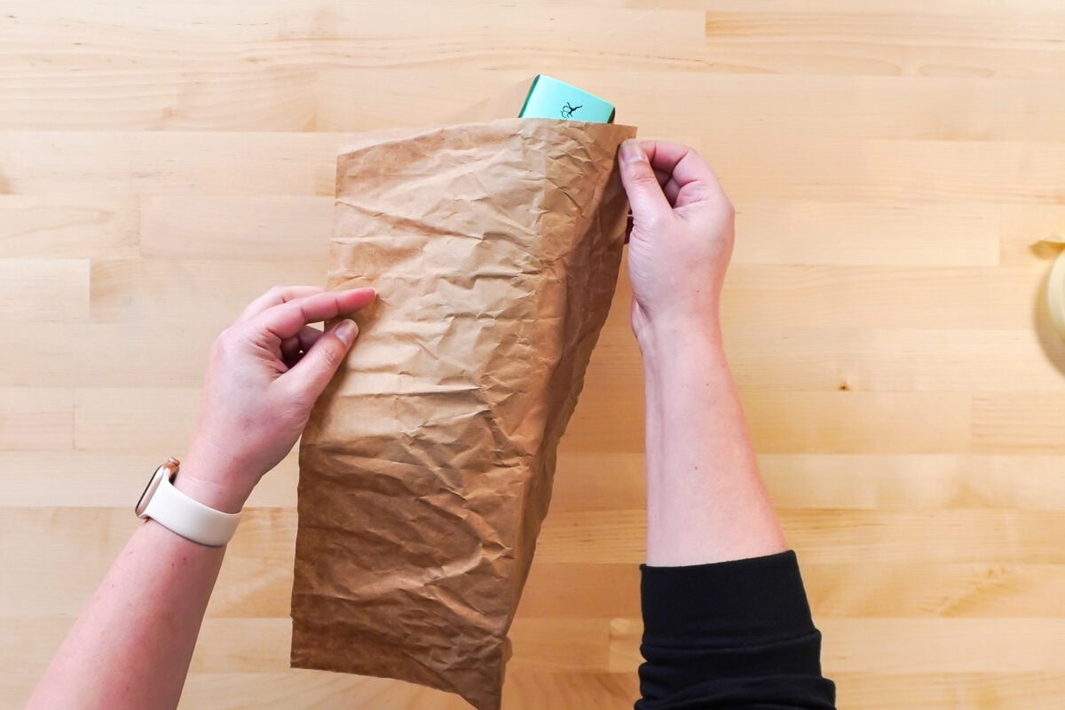 Hands wrapping the book in brown paper