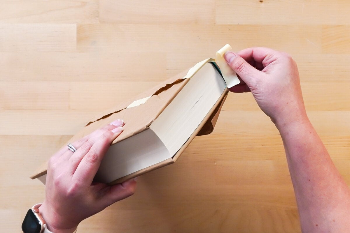 Hands wrapping the book in brown paper