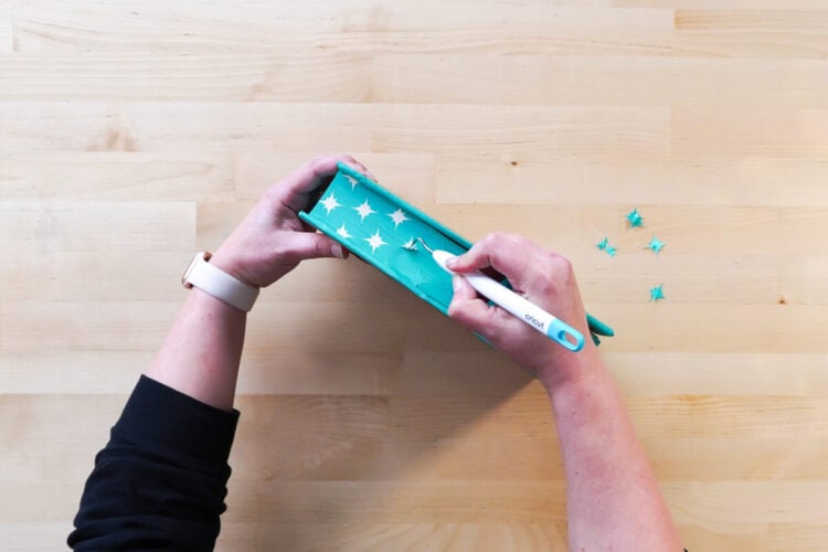 Hands weeding negative star pieces from the design on a sprayed edges book