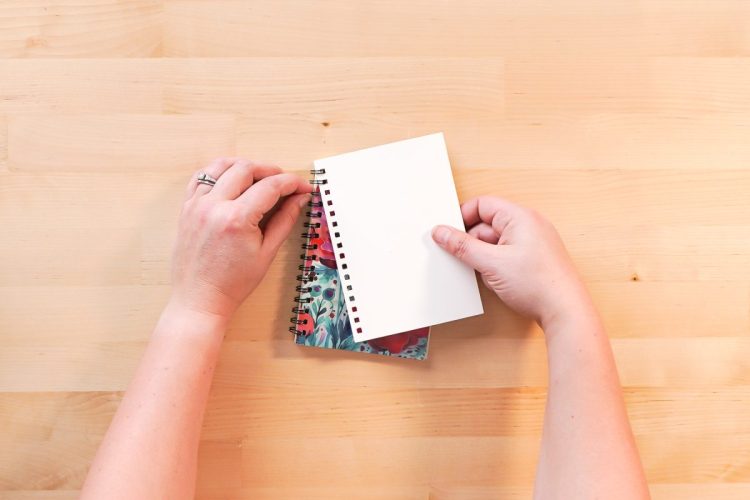 Hands putting the binding back onto a journal
