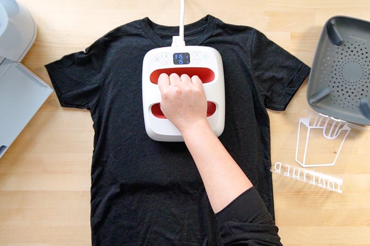 Hands pre-pressing shirt with Cricut EasyPress