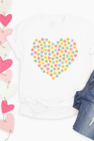 Blue jeans, white tennis shoes, pink and white hearts on a garland and a white t-shirt decorated with small conversation hearts in the shape of a large heart