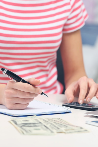 Woman holding pen over a notebook and using a calculator