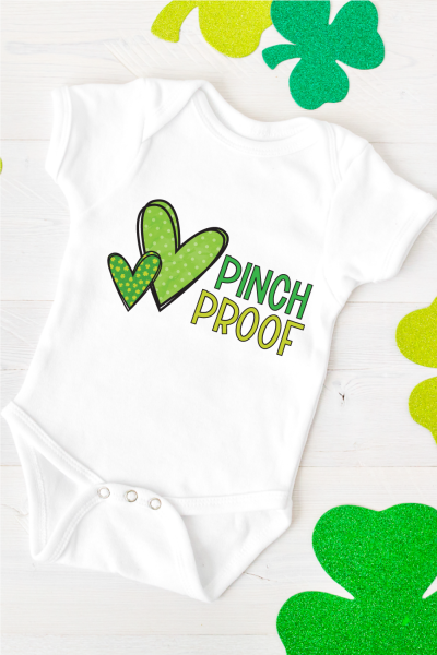 White baby onesie with two green patterned hearts on it and the saying Pinch Proof